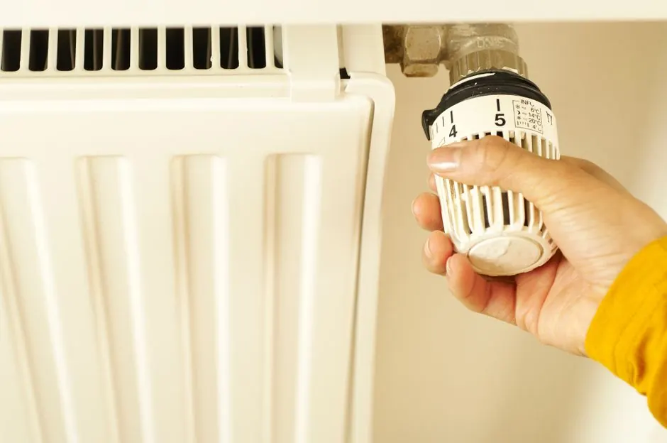 A hand adjusts a thermostatic radiator valve.